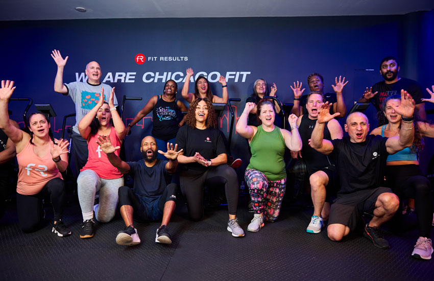 Group of Fit Results members and coaches posing together and smiling inside the training studio