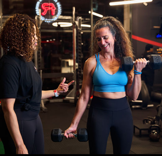 woman lifting weights with help from her trainer